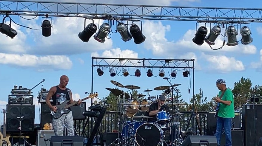 The band Bad bear playing live music on an outdoor stage.