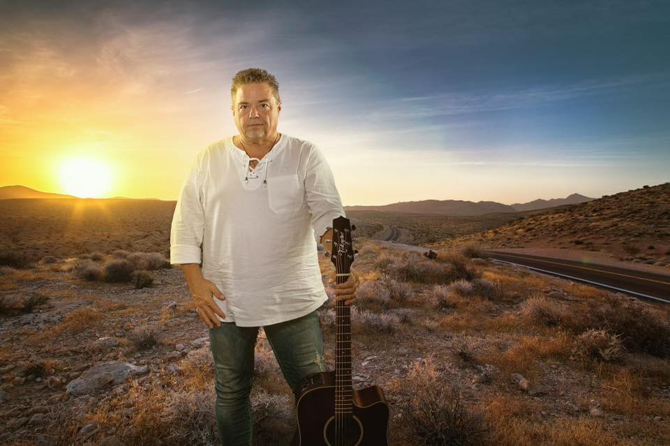 BrianHughes2022 Brian Hughes posing with a guitar in the desert. during sunset.