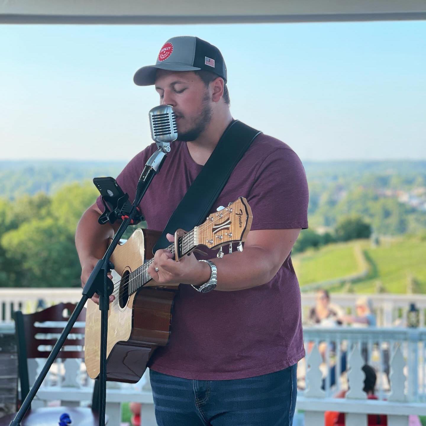 Logan Route playing guitar and signing into microphone.