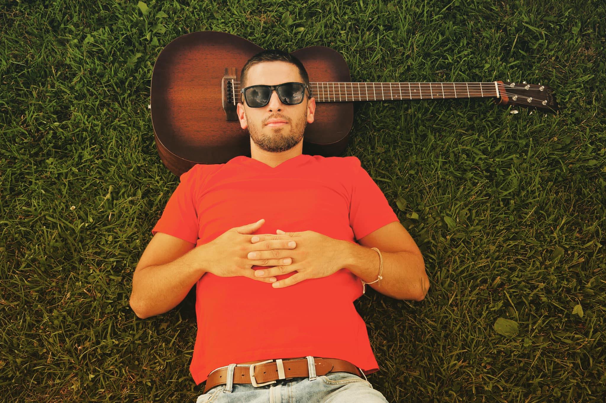 KevinLudwig Kevin Ludwig posing with guitar in grass.