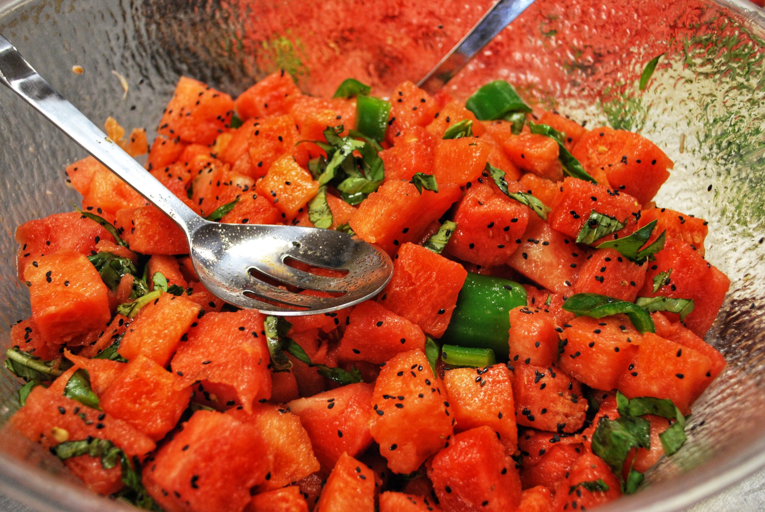 Watermelon Salad with Jalapeños and Lime in a glass serving bowl with a metal serving spoon.